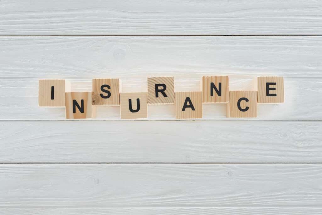 Word “insurance” on wooden wood tiles.