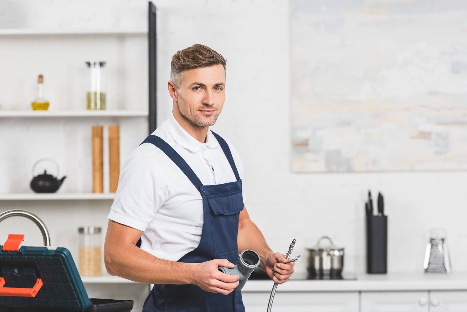 A plumber holding pipes for kitchen faucet repair.
