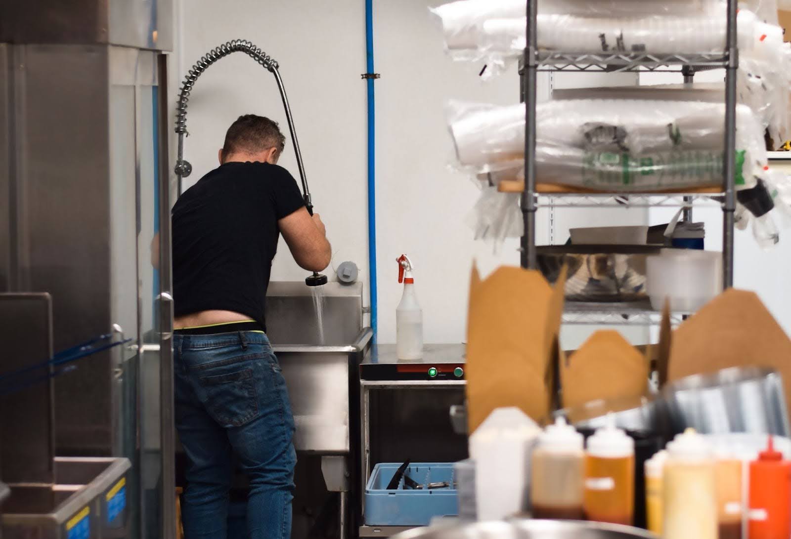 Rear view of a restaurant crew washing dishes in a large industrial sink.