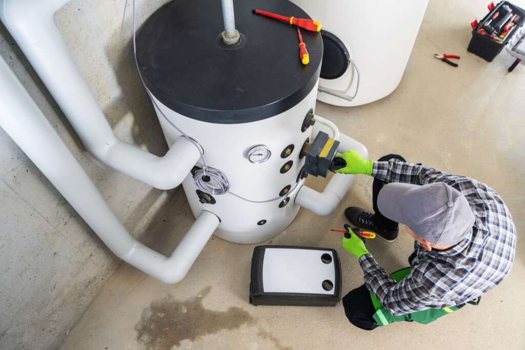 Top view of a technician servicing a residential water heater system.