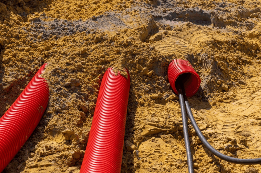 Red PVC plumbing pipe and drainage tubing prepared for sewer line repair work.