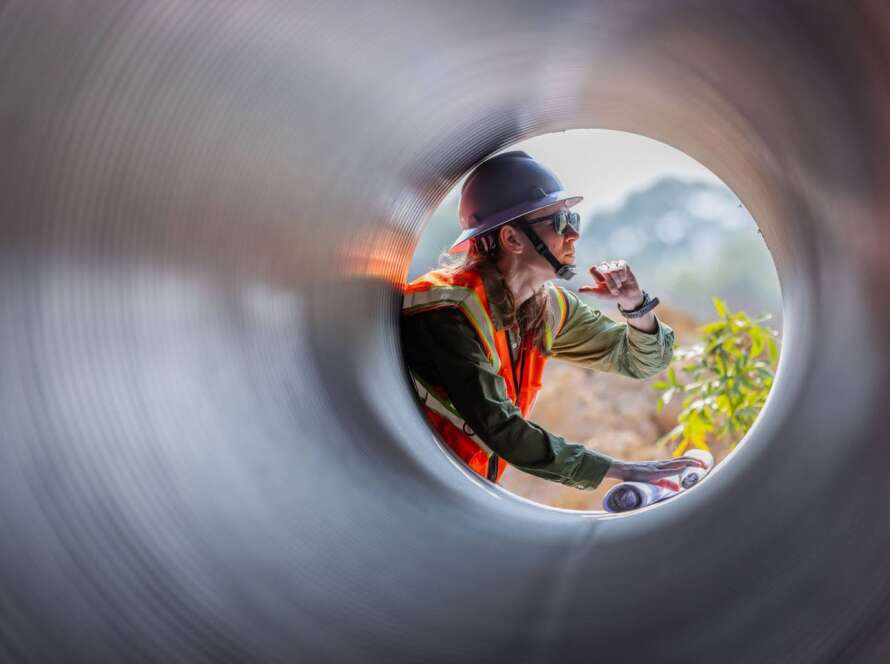 An engineer is seen through the open end of a new sewer pipe during a replacement.