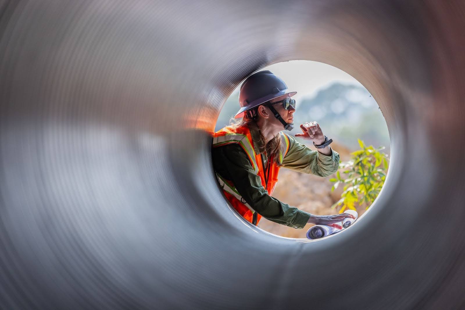 An engineer is seen through the open end of a new sewer pipe during a replacement.