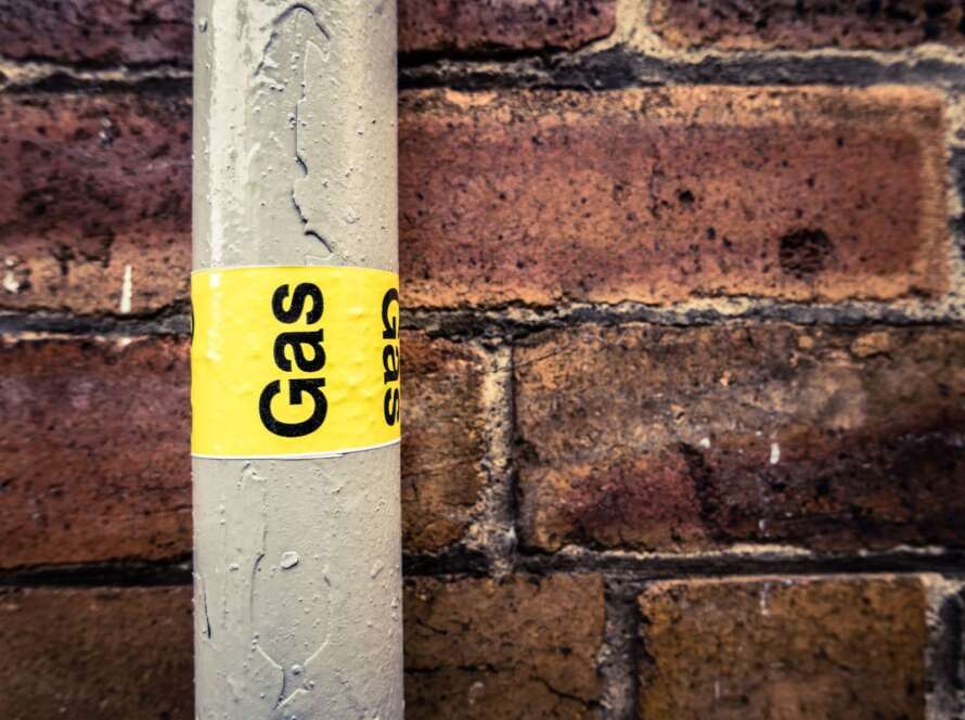 Extreme close up on a residential gas pipe with yellow tape that reads ‘gas.’
