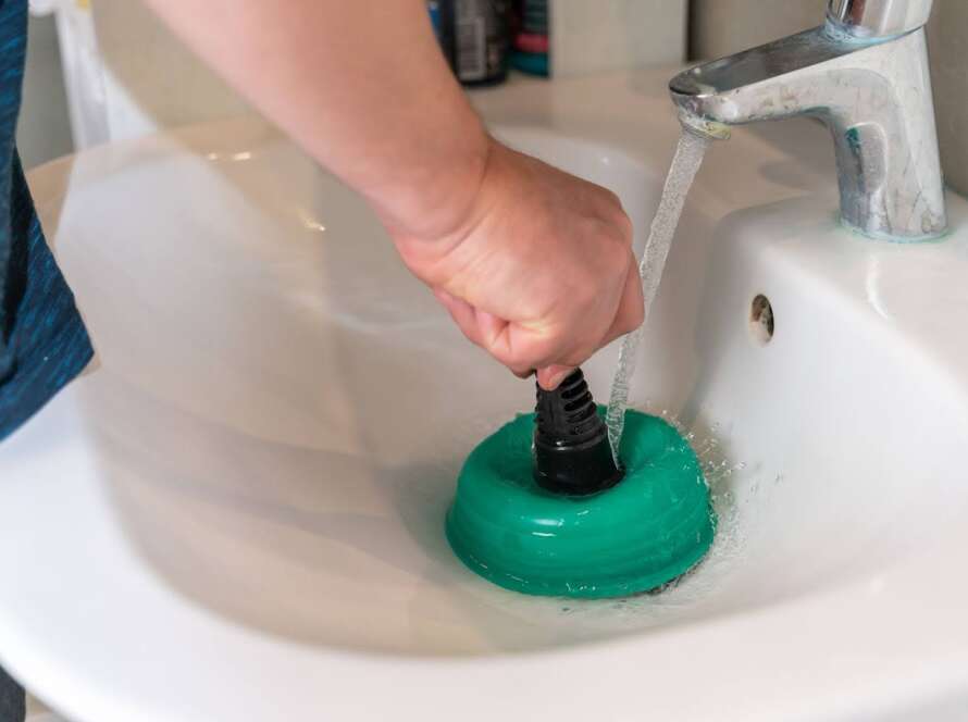 Person using a tool to unclog a drain.