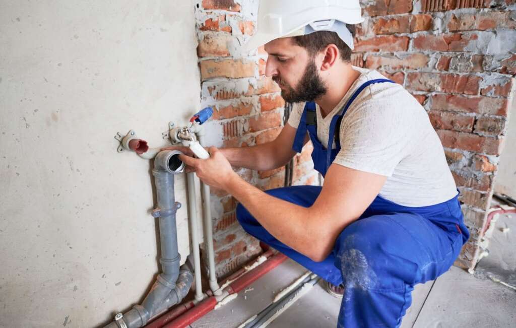 Plumber repairing a sewer pipe using sealant to prevent leaks in a home plumbing system.