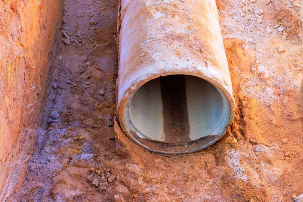 During a construction job, a concrete sewer pipe is exposed from the dirt.