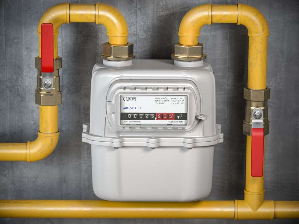 A natural gas meter with yellow tubes up against the wall of a home.